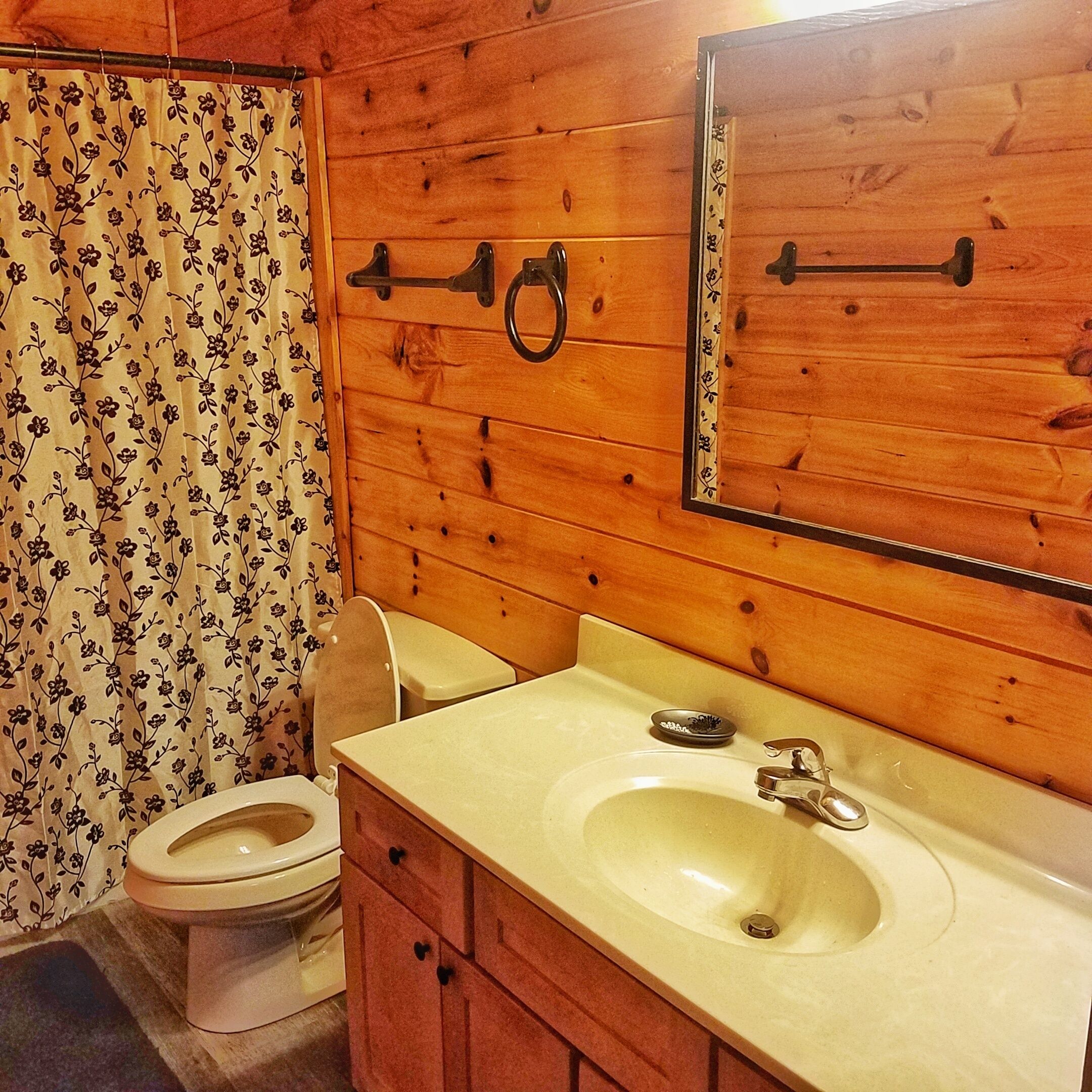 Un baño de madera con inodoro, lavamanos y espejo.