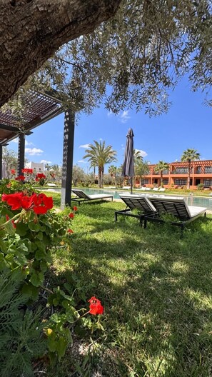Ein Poolbereich mit Liegestühlen, einer Pergola und einem Gebäude im Hintergrund.