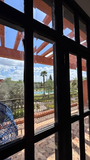 Blick durch ein Fenster mit Metallgitter, ein klarer Himmel und ein entferntes Gebäude.