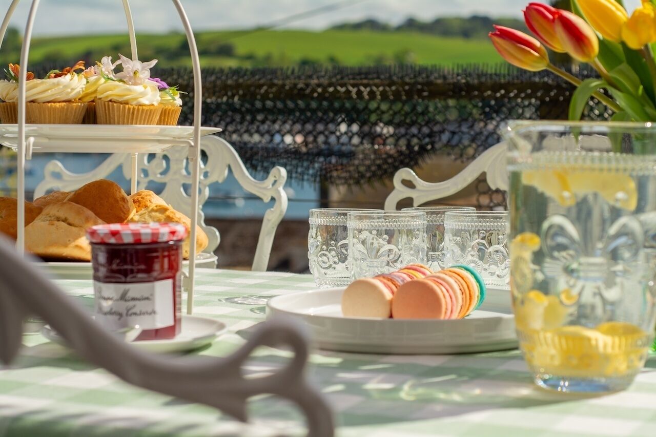 A table with pastries, a jar of jam, and a glass with a lemon slice.