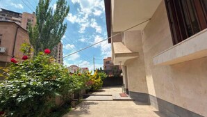 A narrow alleyway with a concrete path, surrounded by buildings and vegetation.