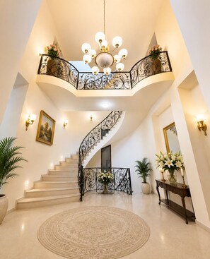 A grand staircase with ornate railings, a chandelier, and a round carpeted area. - Dreams House Hostel & Hotel (Yerevan)