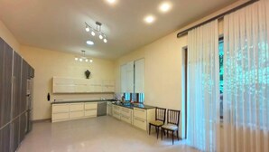 A spacious kitchen with modern appliances, a dining area with chairs, and a large window with curtains.