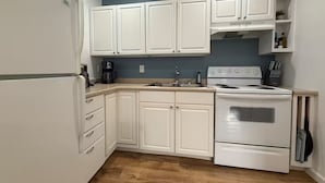 A kitchen with white cabinets, a stove, and a coffee maker. - Boone Adventure Hub: Spacious Studio Near Trails & Parkway (Boone)