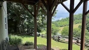 A covered patio with a bench, wooden beams, and a view of a green landscape with trees and a fence. - Boone Adventure Hub: Spacious Studio Near Trails & Parkway (Boone)