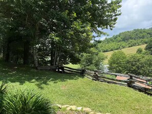 A lush green landscape with a river, trees, and a stone wall. - Boone Adventure Hub: Spacious Studio Near Trails & Parkway (Boone)