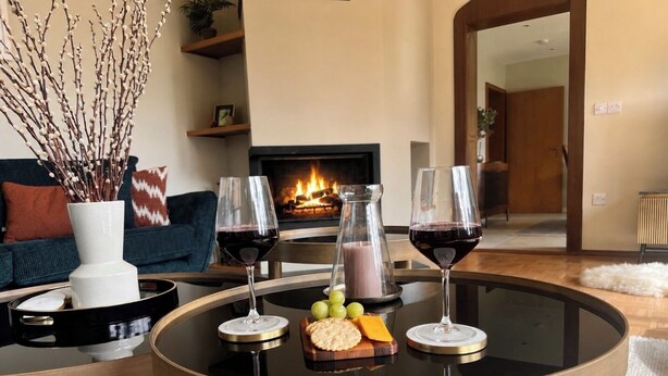 Ein runder Glastisch mit Tablett, zwei Weingläsern, einer Flasche und einer Platte mit Käse und Trauben.