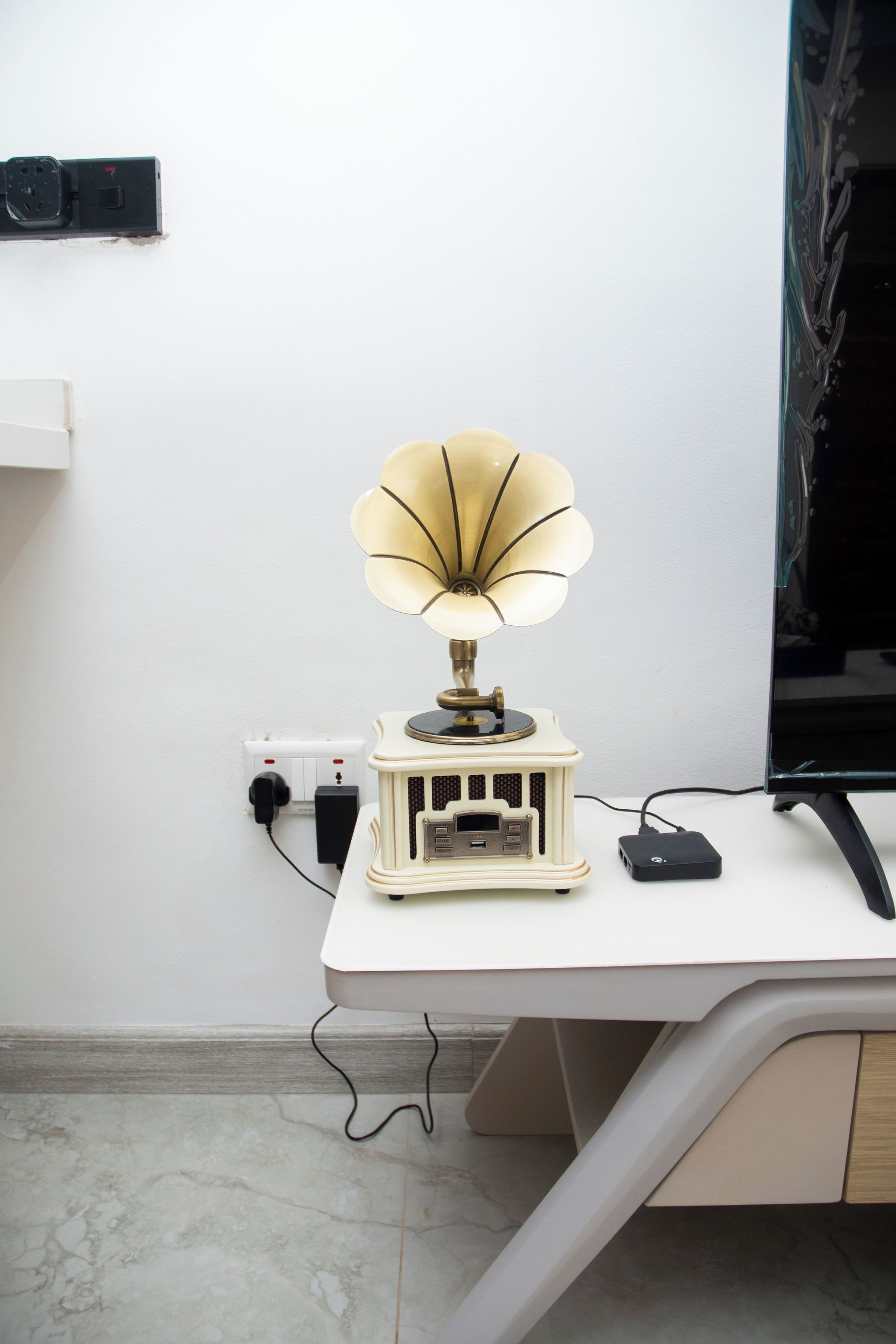 Un bureau agrémenté d’une lampe de style vintage, d’un écran d’ordinateur et d’une multiprise.