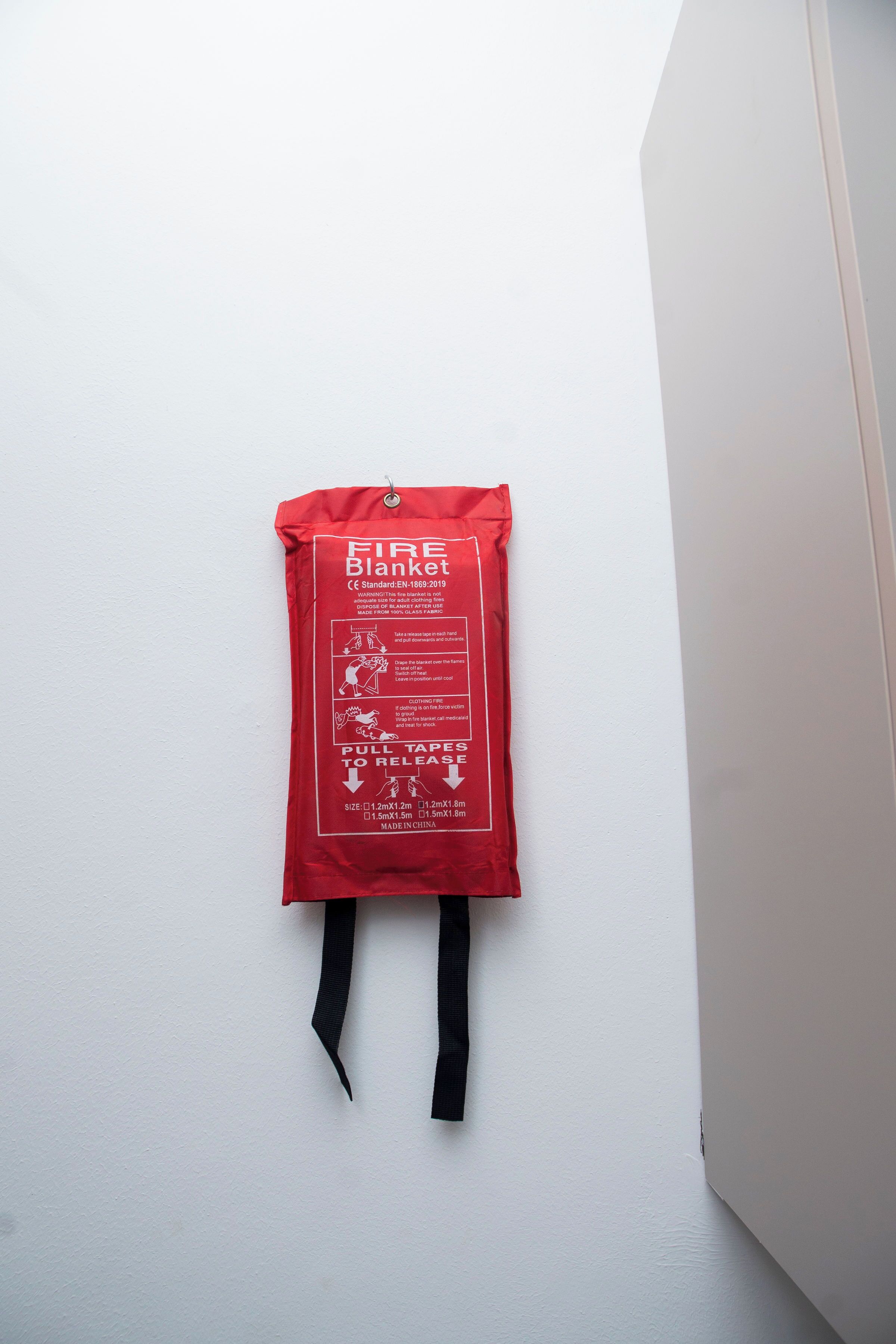 A red fire blanket hanging on a white wall.