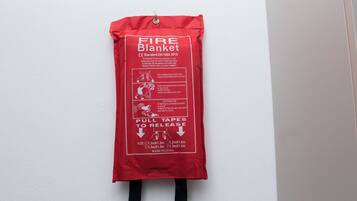 A red fire blanket hanging on a white wall.
