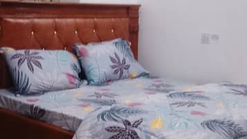 Una cama individual con una colcha de estampado floral, un cabecero de madera y una alfombra roja en el suelo.