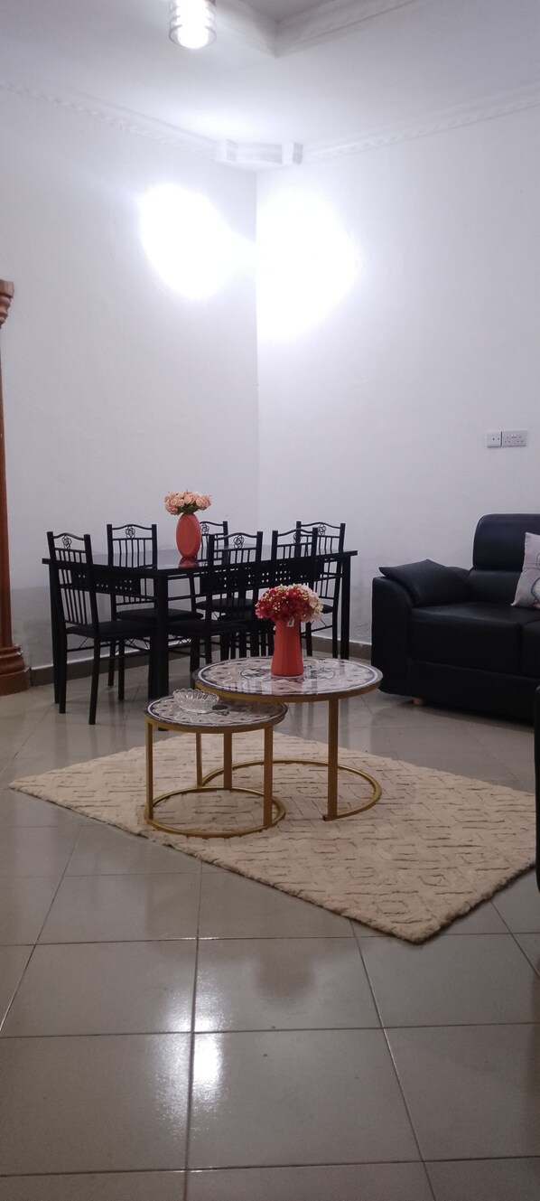 A living room with a dining table, chairs, a sofa, a coffee table, and a rug.