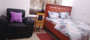 Ein Schlafzimmer mit einem Bett, einem Sessel und einem Fenster.