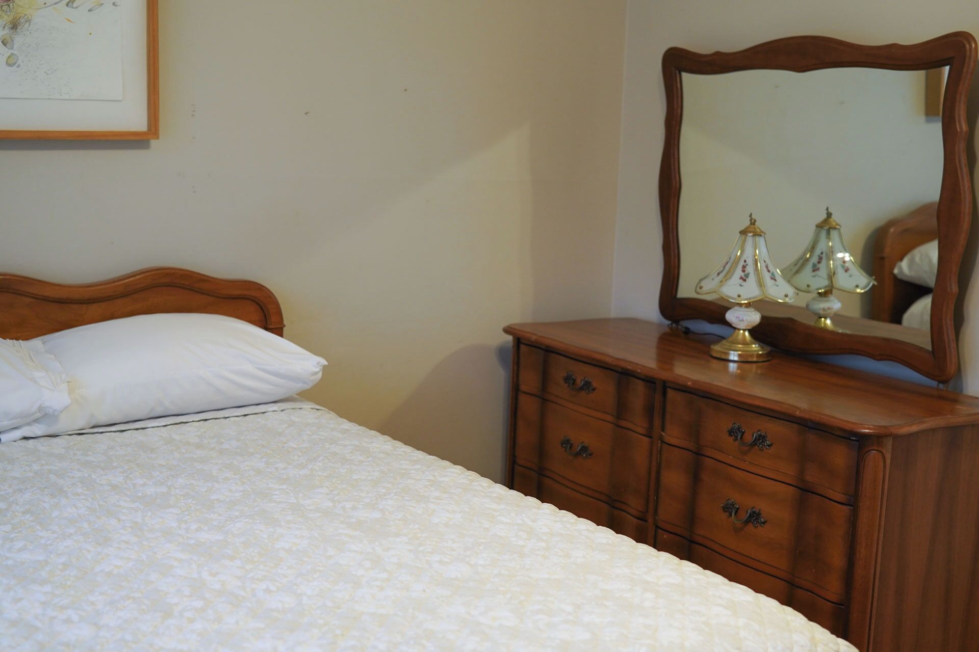 A bedroom with a bed, a dresser with drawers, and a mirror.