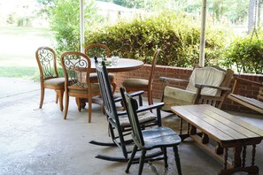 Un patio al aire libre con una mesa redonda y sillas, un banco y un muro de ladrillo.