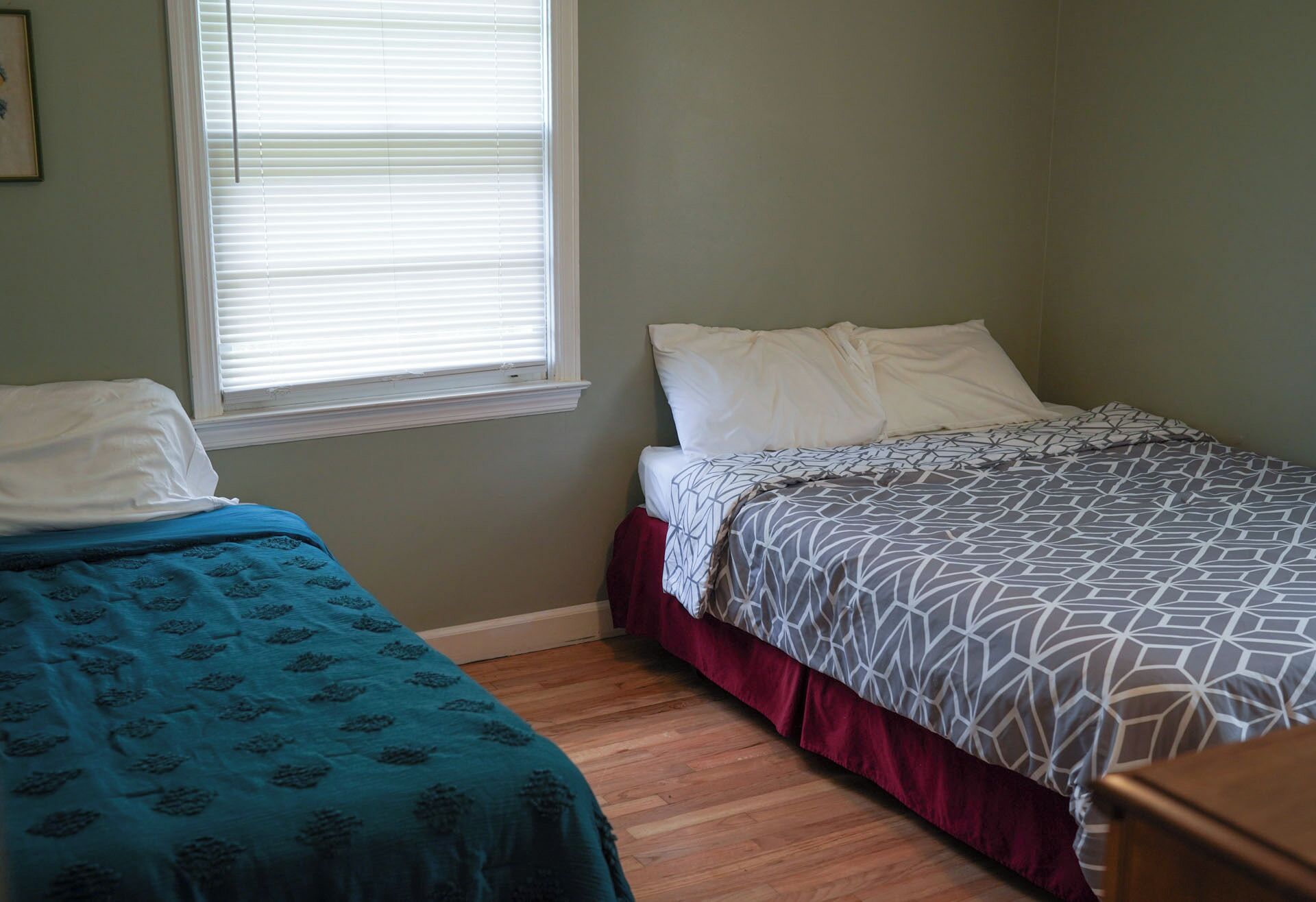 Une chambre à coucher avec deux lits simples, l’un recouvert d’une couvre-lit bleue et l’autre d’une couvre-lit à motifs.