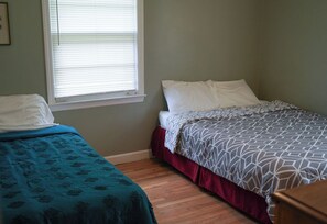 A bedroom with two single beds, one with a blue bedspread and the other with a patterned bedspread.