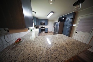 Una cocina con encimeras de granito, electrodomésticos de acero inoxidable y armarios azules.