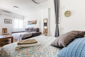 Quarto com cama, sofá, escrivaninha e um quadro na parede.