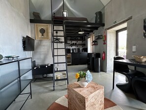 A modern interior with a loft bed, kitchen area, and a dining space. - THE L Lodge, Ocean View Private Garden Cottage (Tabua)