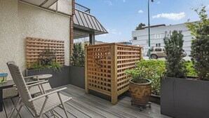 Un balcon agrémenté de meubles en osier, d’une cloison en treillis de bois et de plantes en pot.
