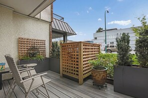Ein Balkon mit Korbmöbeln, einem Holzzapfen und Topfpflanzen.