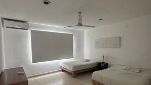 A bedroom with a bed, a bedside table, a nightstand, a ceiling fan, and a large window.