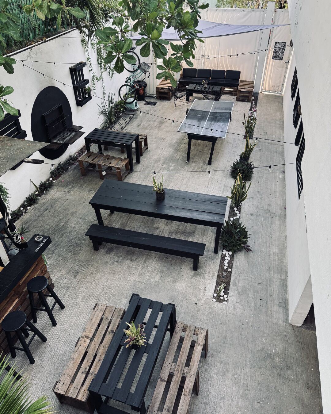 Un patio exterior con varias zonas de estar, una parrilla y una mesa con una planta en maceta.