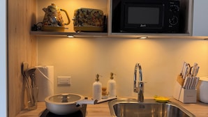 A modern kitchen with a microwave, kettle, and a bowl on the counter.