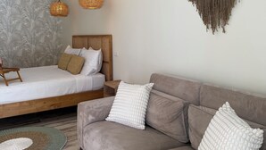 A modern bedroom with a bed, a sofa, a macrame wall hanging, and two woven pendant lights.