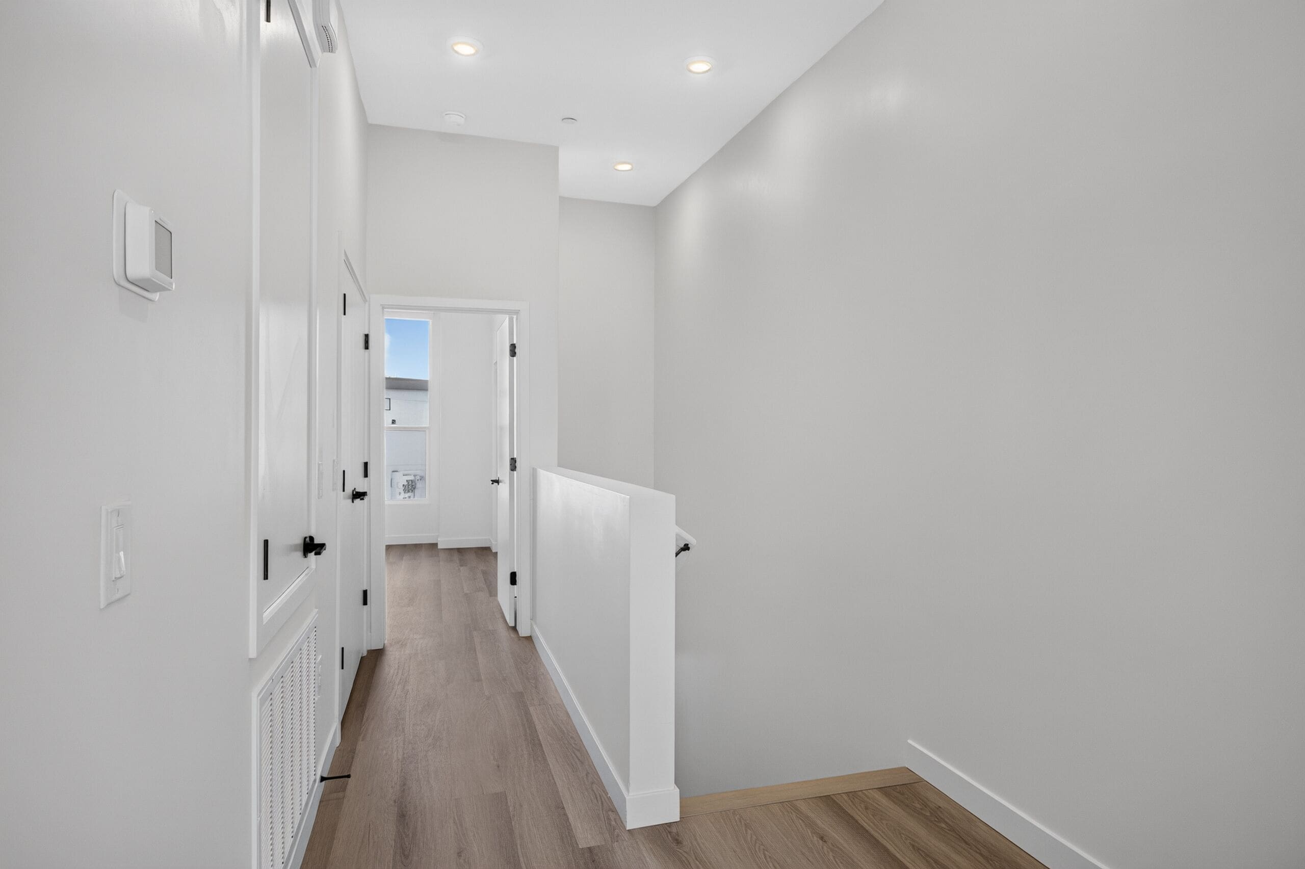 Un couloir aux murs blancs, avec un radiateur et une porte donnant sur une autre pièce.