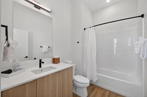 Une salle de bain moderne équipée d’un lavabo, d’un miroir, de toilettes et d’un espace douche.