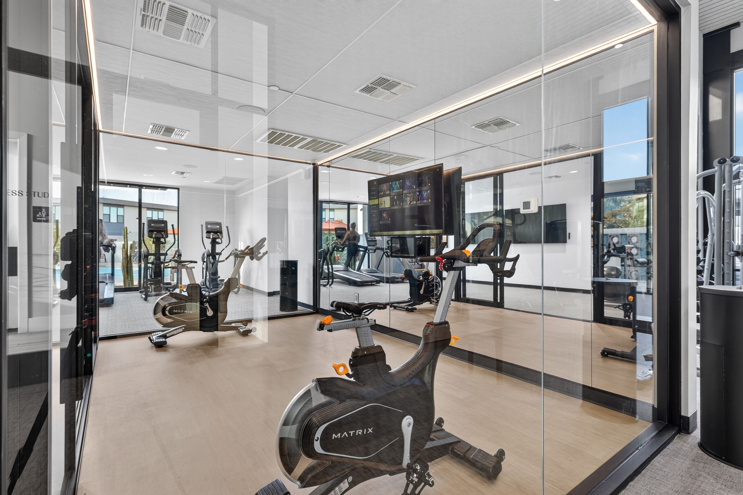 A gym with exercise equipment, a large mirror, and a television screen.