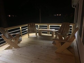 A wooden deck with two Adirondack chairs and a bench, surrounded by a railing. - Sirena's Isle Waterfront
boat lift, pet friendly (Oriental)