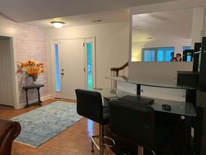 A modern living room with a glass-top dining table, a black office chair, a brown leather sofa, and a blue rug. - Sirena's Isle Waterfront
boat lift, pet friendly (Oriental)