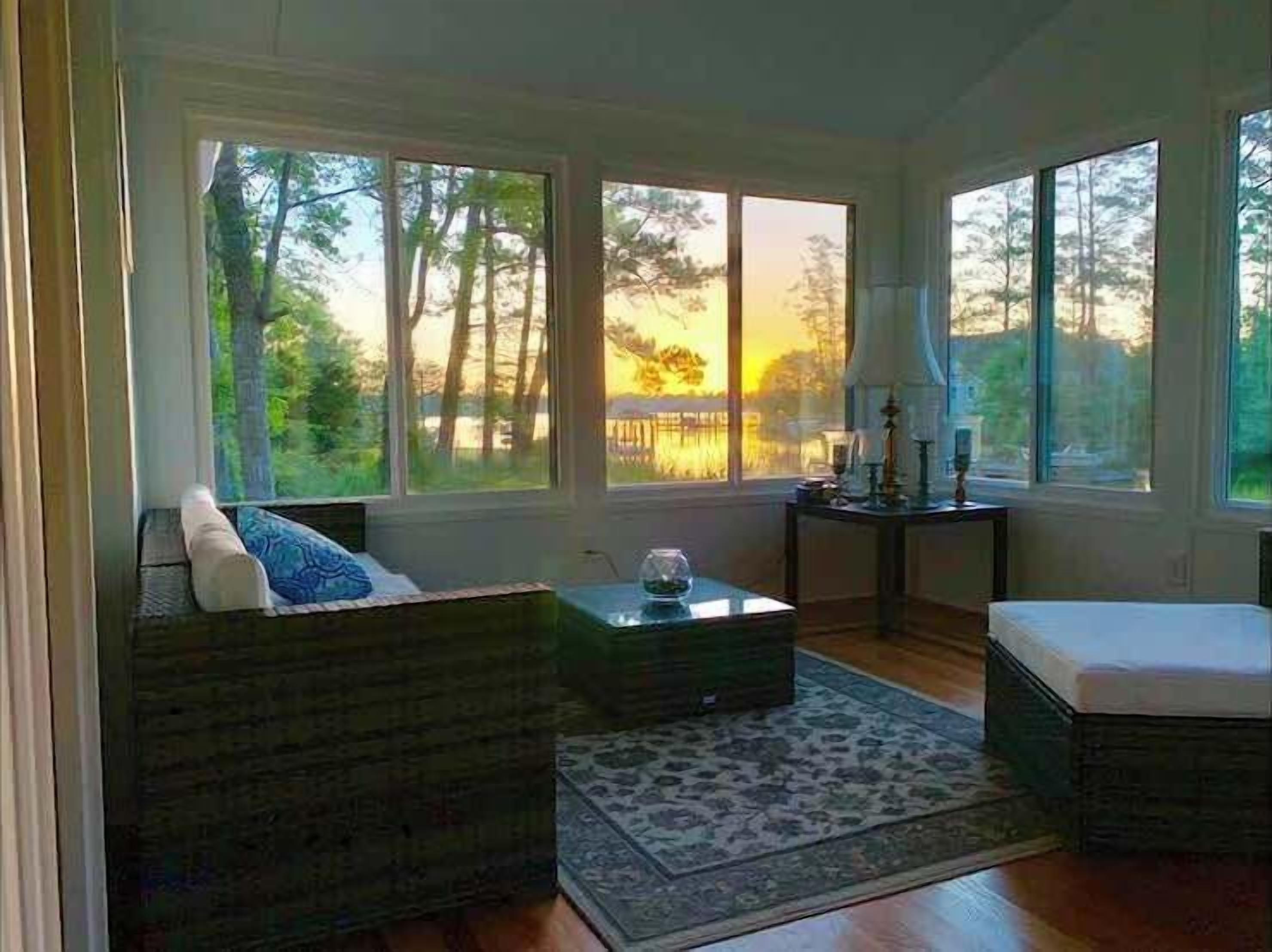 A room with a large window, a sofa, a small table, and a rug.