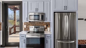 Una cocina moderna con armarios grises, un refrigerador de acero inoxidable, un microondas y un horno.