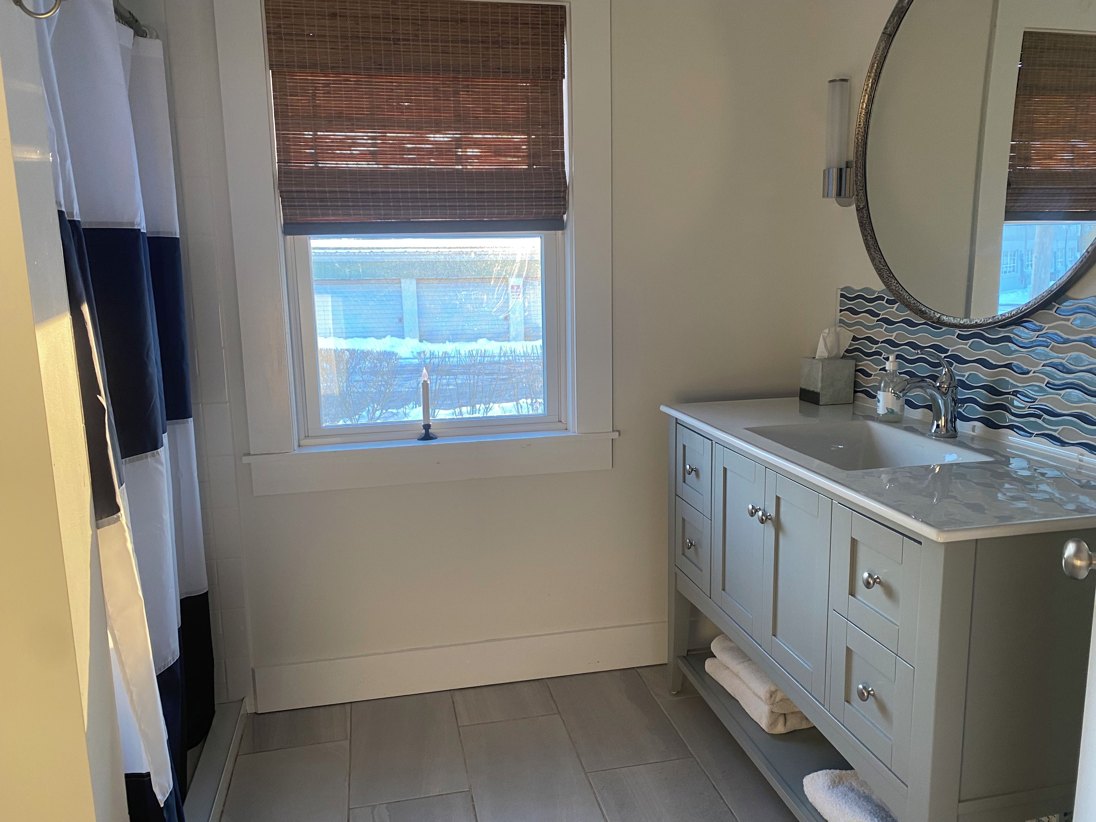 Ein Badezimmer mit Fenster, Waschbecken, Spiegel und Handtuchhalter.
