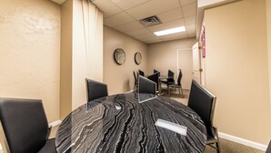 Une salle de conférence avec une table en marbre, des chaises noires et une porte au fond.