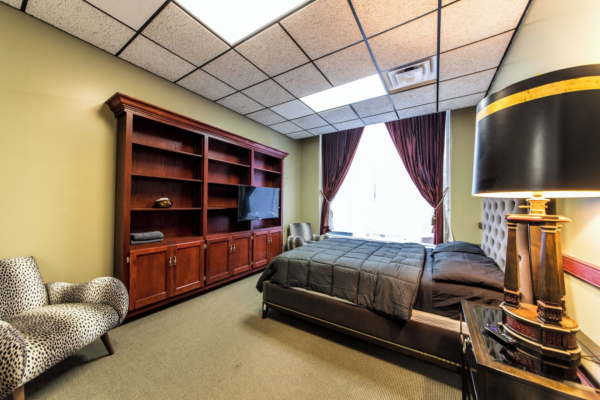 Une chambre d’hôtel avec un lit, une télévision, une armoire, une chaise et une lampe.