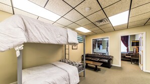 Une chambre avec un lit superposé, un miroir, un canapé en cuir et une porte donnant sur une autre pièce.