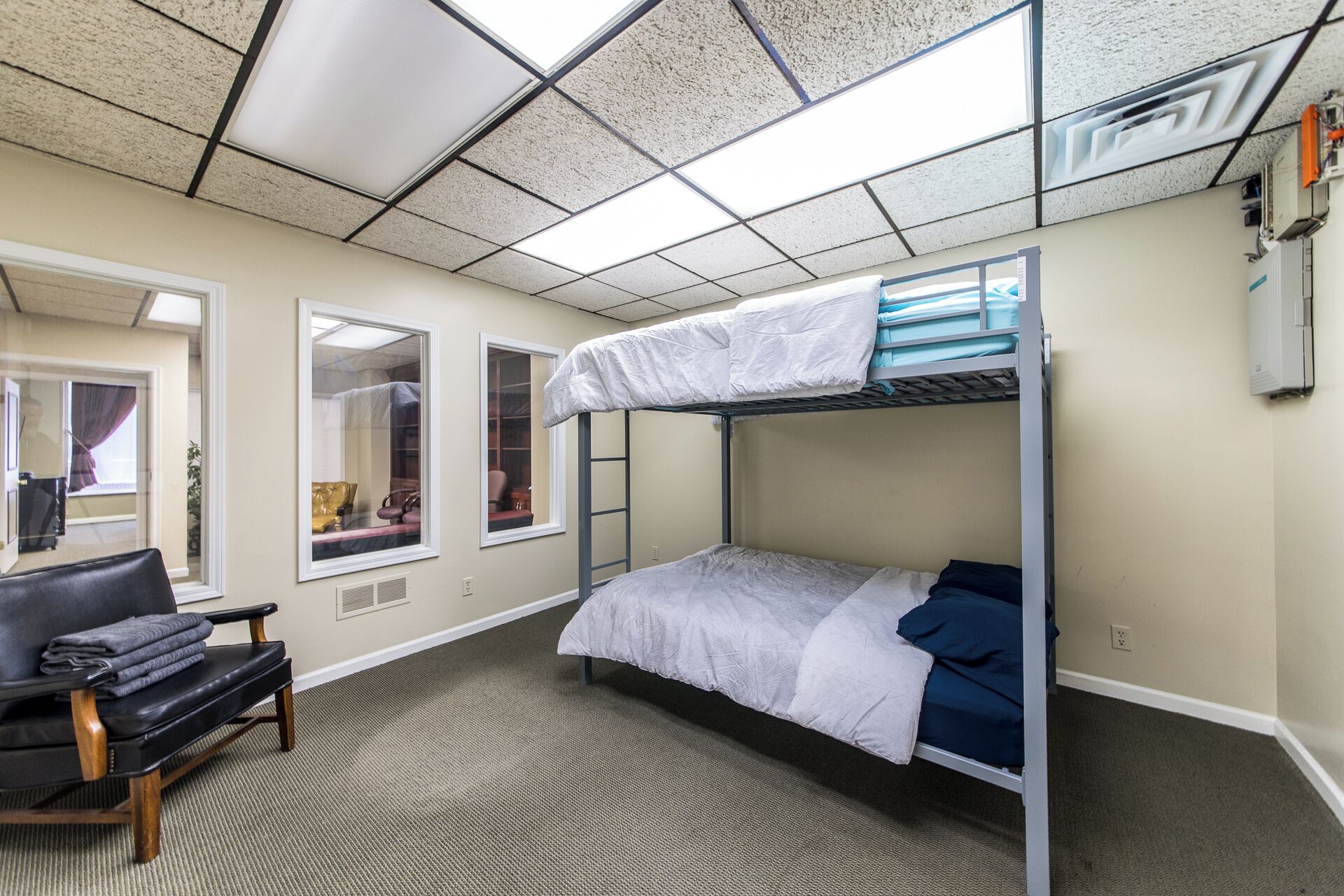 A bunk bed room with a window, a chair, and a radiator.