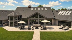 Ein modernes Haus mit einer großzügigen Terrasse, Gartenmöbeln und einer überdachten Sitzecke.