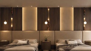 Ein modernes Schlafzimmer mit zwei Betten, Holz-Kopfteilen und Pendelleuchten.