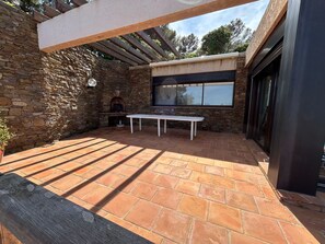 A stone-walled patio with a brick floor, a white table, and a stone oven. - Beachfront Home (Bormes-les-Mimosas)