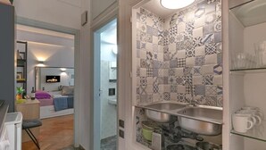 Et kompakt køkken med to vaske, en indbygget ovn og et flisebeklædt bagpanel.