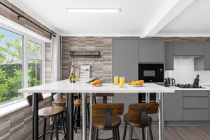 Una cucina moderna con un'isola centrale, sgabelli da bar, un forno a microonde e un piano cottura a gas.
