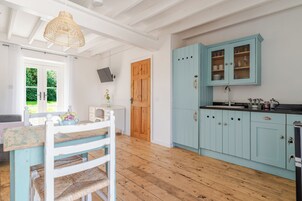 A kitchen with light blue cabinets, a wooden dining table, and a wicker chair.