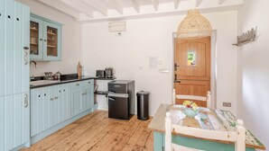 Una cocina con armarios azul claro, un refrigerador negro y una puerta de madera.