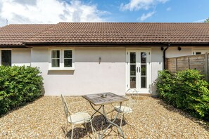 A house with a tiled roof, a gravel patio, and a table with chairs. - Lily of the Valley (Keynsham)